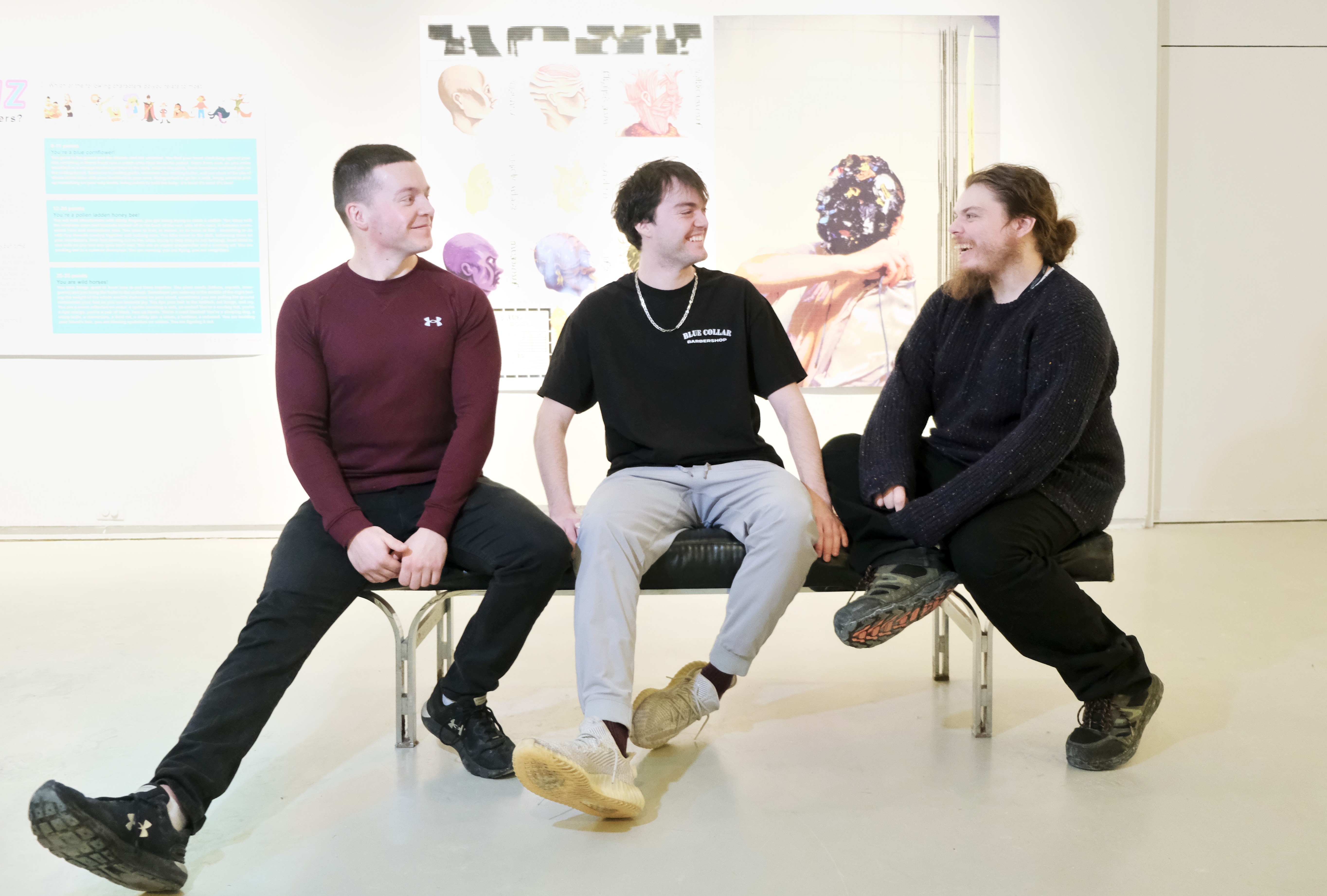 Three male students sit on a bench in conversation with each other