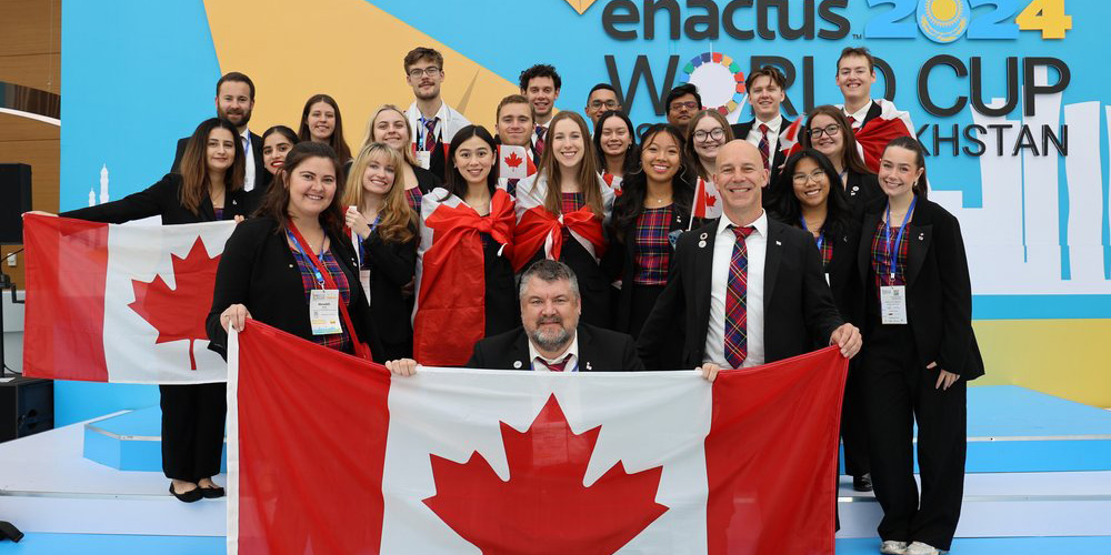 Celebrating students surround a Canadian flag.