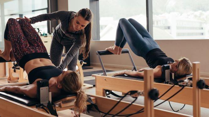 Instructor Assisting Client on a Pilates Reformer