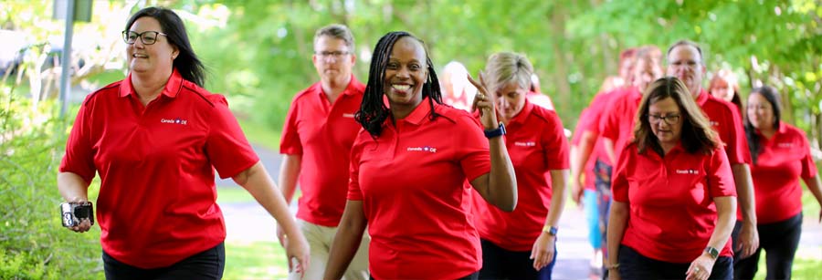 Group of adults, all in red shirts, out for a walk.