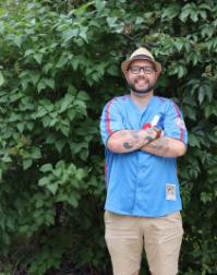 Photograph of alumnus James Urquhart in front of greenery