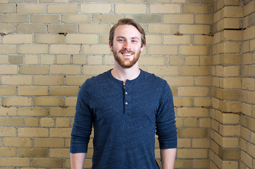 Josh MacIntyre standing in front of a brick wall.