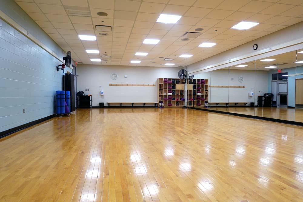 Studio A. Dance style studio with hardwood floor and mirrored wall to the left.