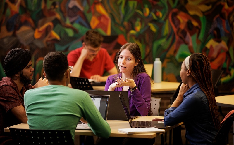 A photo of student Theressa Jabour talking to a few other students in the Patrick Power Library